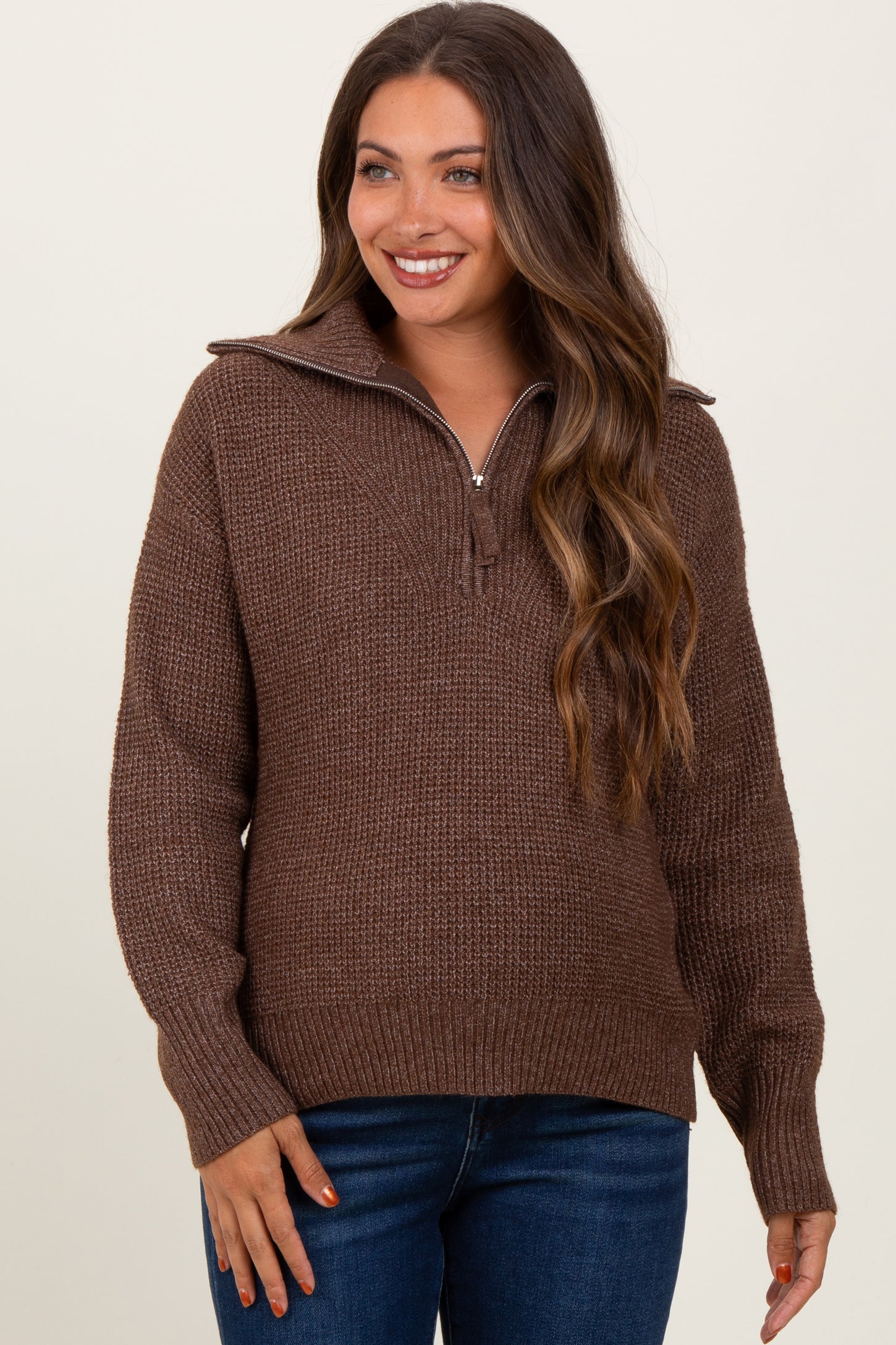 woman wearing a brown textured maternity sweater with a half-zip and relaxed fit, smiling at the camera