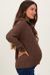 woman wearing a brown knitted maternity sweater, smiling with hands on her pregnant belly