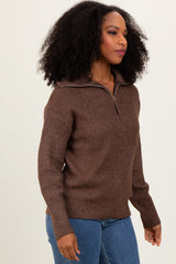 woman wearing a brown half-zip sweater with a textured design and ribbed hem, paired with blue jeans