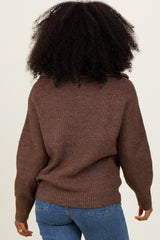 woman wearing a brown oversized knit sweater and blue jeans, seen from the back