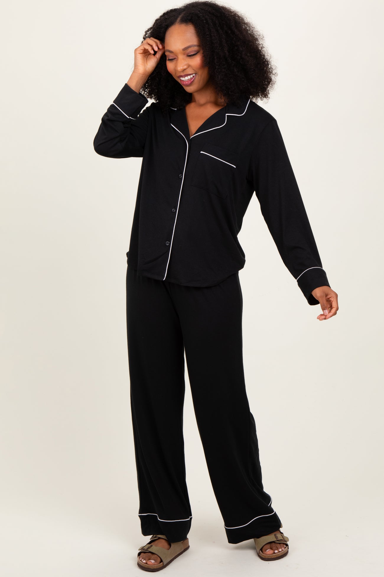 woman wearing a black long sleeve pajama set with white piping and relaxed-fit pants