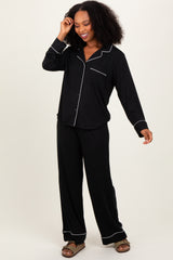 woman wearing a black long sleeve pajama set with white piping and relaxed-fit pants