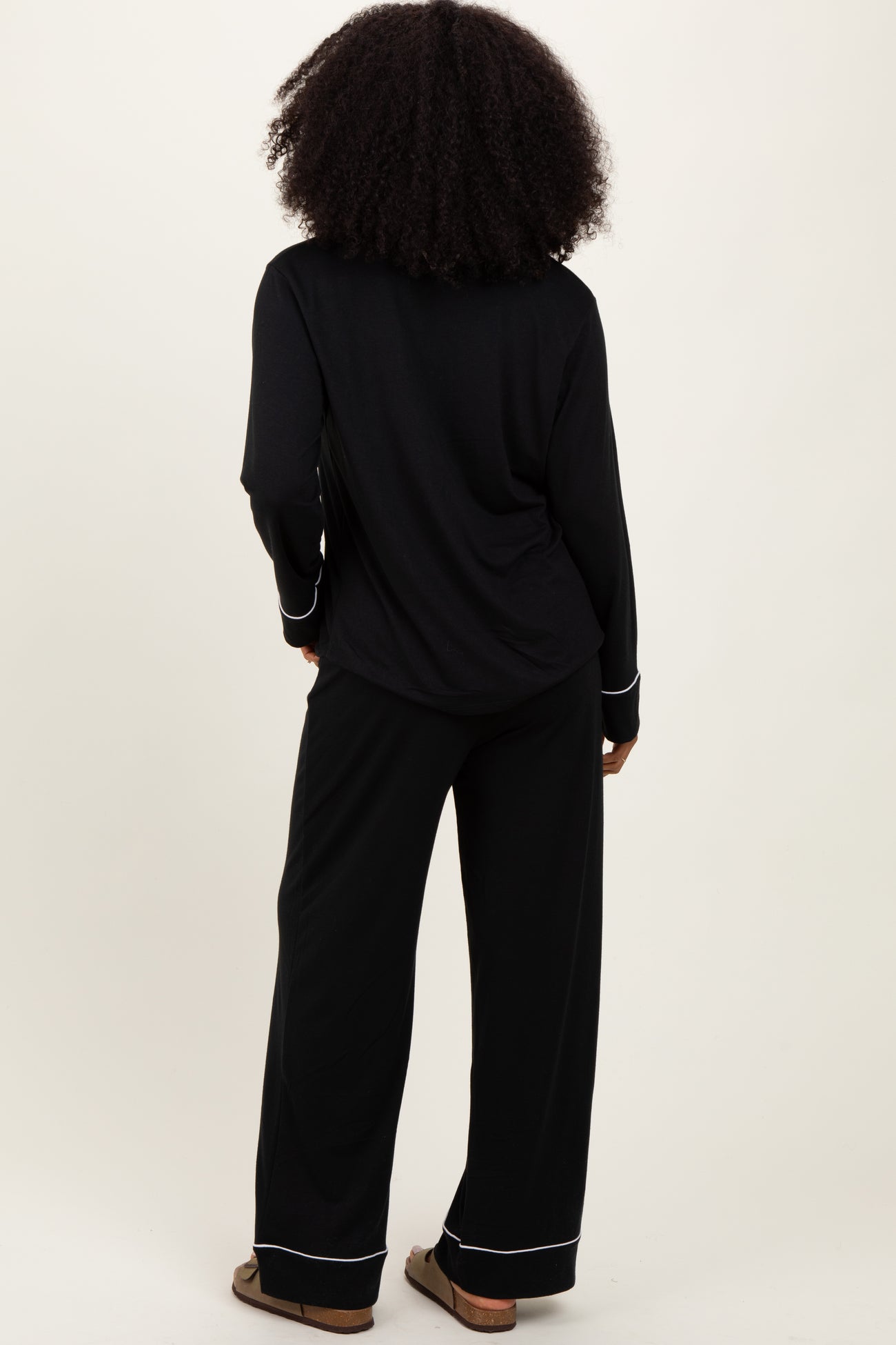 woman wearing a black long sleeve pajama top and matching wide-leg pants, seen from the back