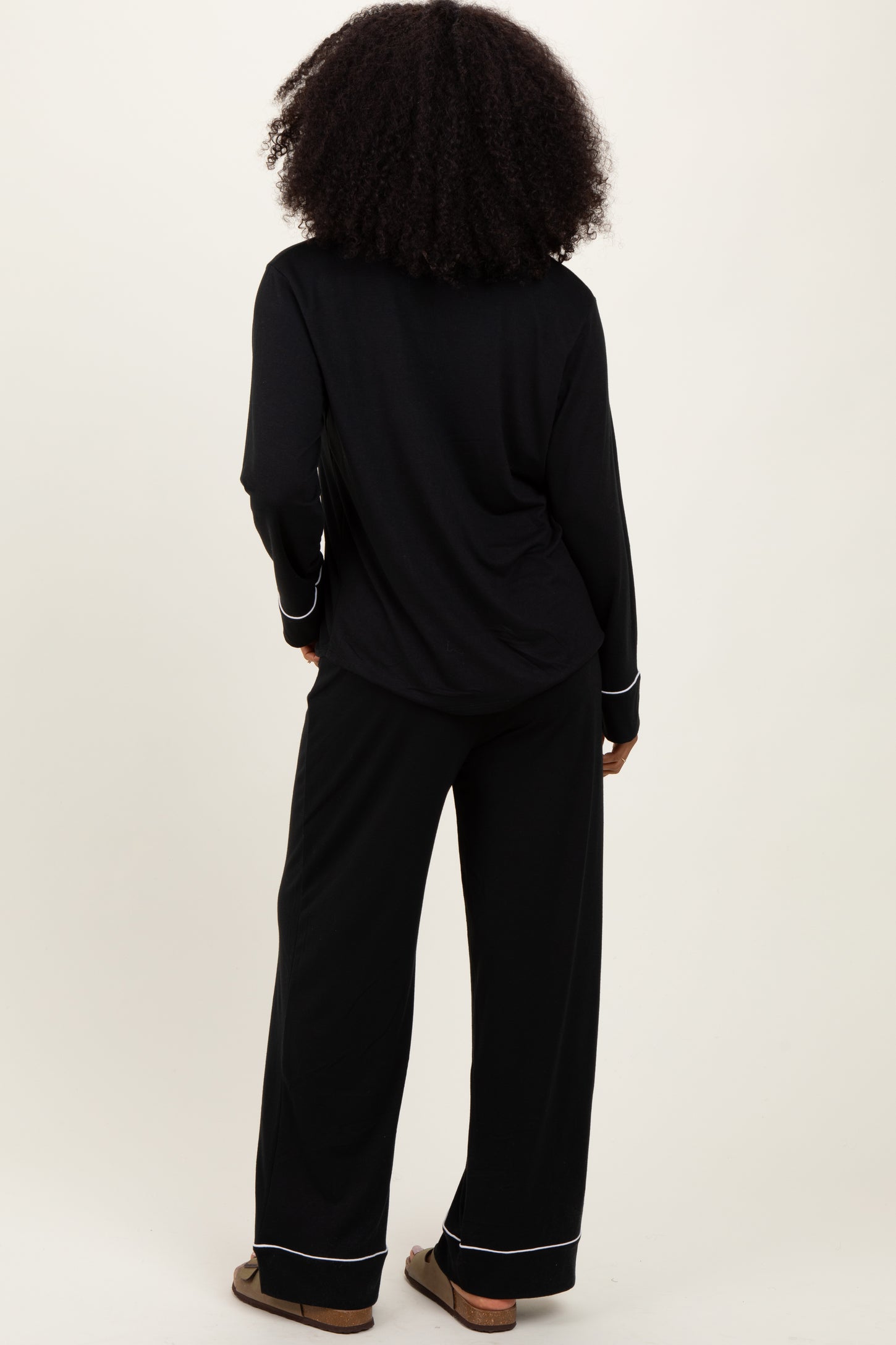 woman wearing a black long sleeve pajama top and matching wide-leg pants, seen from the back