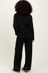woman wearing a black long sleeve pajama top and matching wide-leg pants, seen from the back