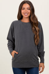 woman wearing a dark gray maternity sweatshirt with side pockets and raglan sleeves, showing a baby bump