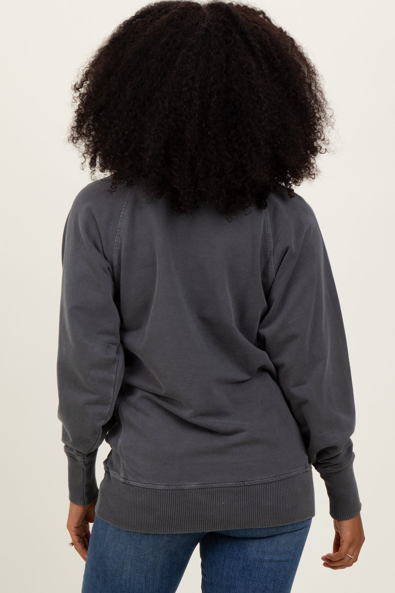 woman wearing a gray oversized sweatshirt, viewed from the back with a relaxed fit and ribbed cuffs