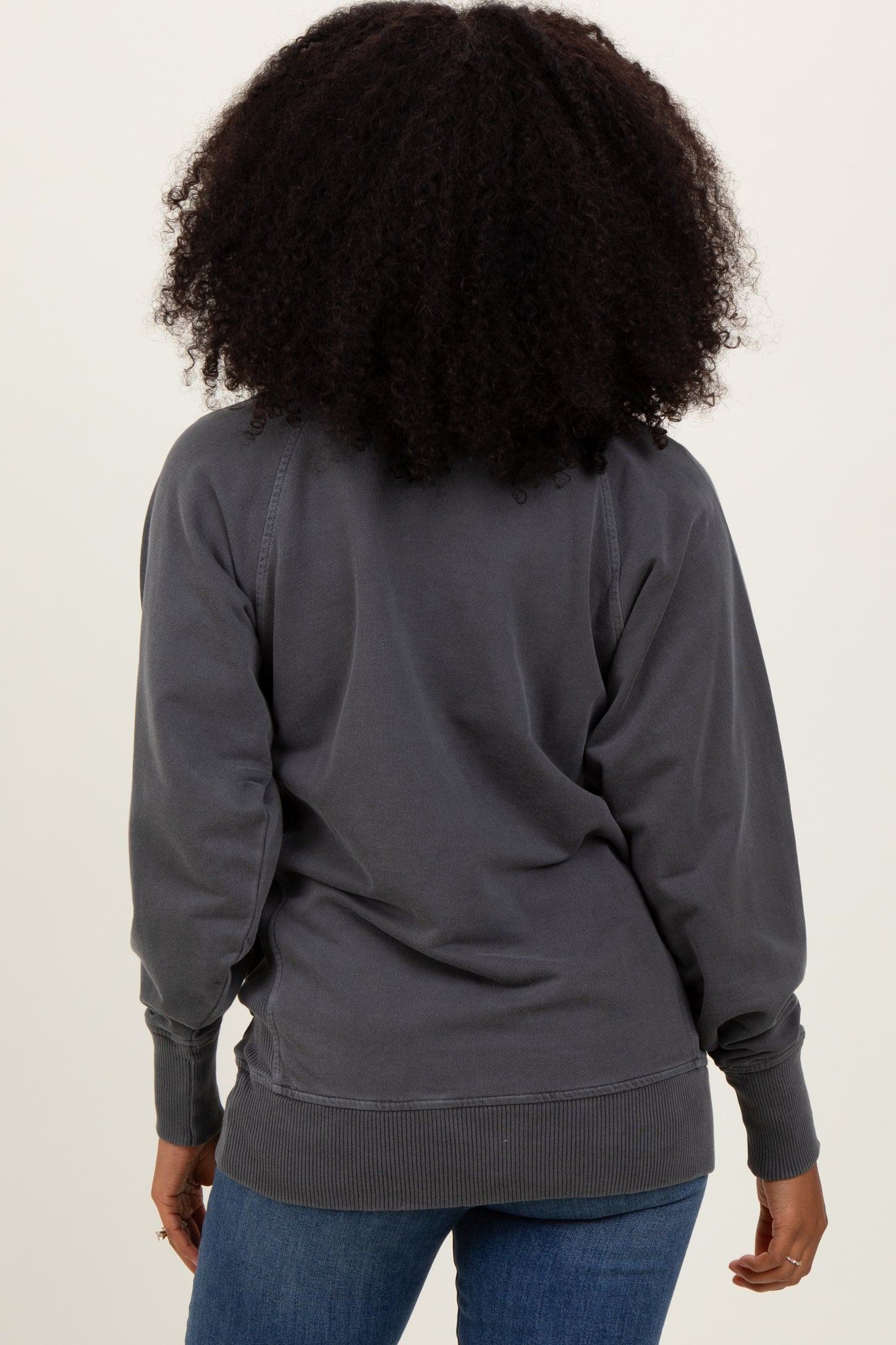 woman wearing a gray oversized sweatshirt, viewed from the back with a relaxed fit and ribbed cuffs