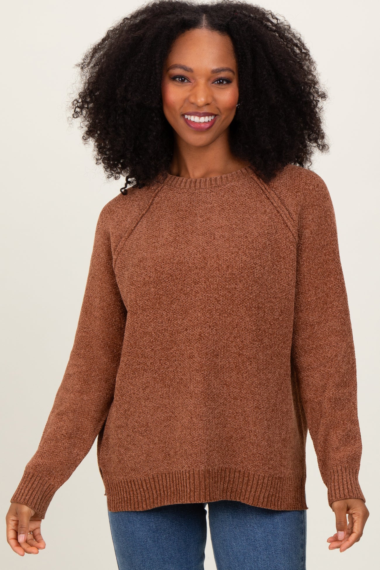 woman wearing a brown cozy knit sweater with raglan sleeves and a relaxed fit, smiling at the camera