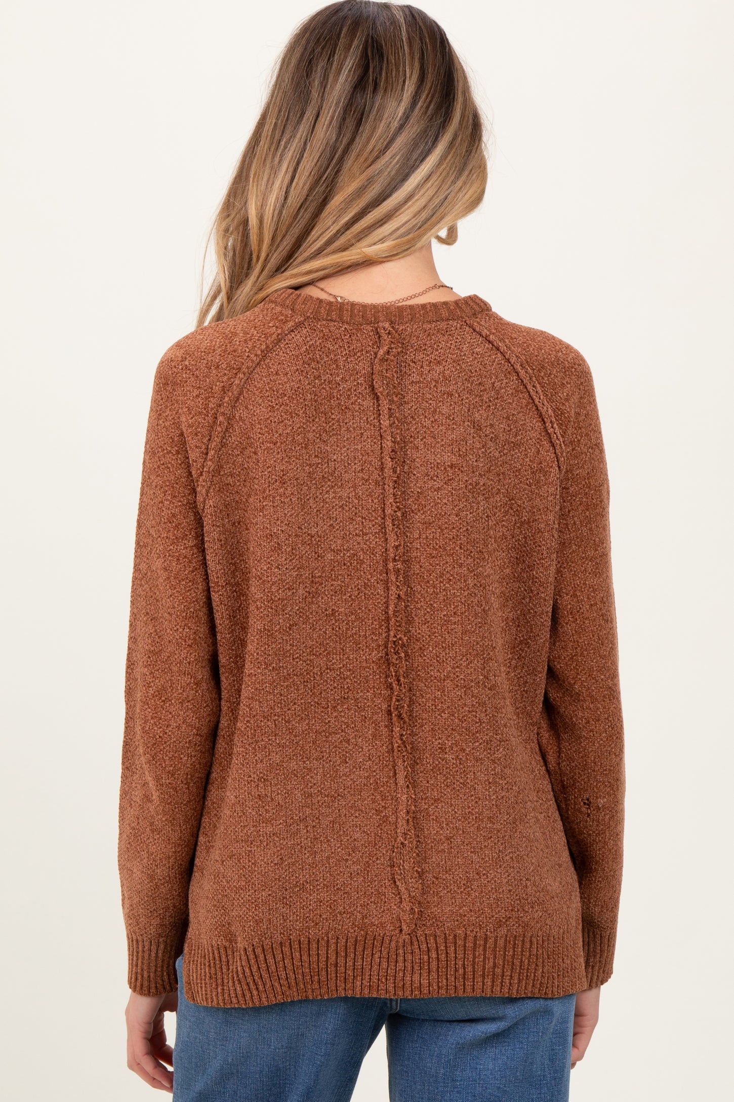 woman wearing a burnt orange maternity sweater with a textured finish and a relaxed fit, shown from the back