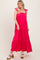 woman wearing a bright pink maxi dress with tie shoulder straps and a tiered design