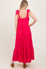 woman wearing a bright pink maxi dress with tie shoulder straps and tiered ruffle skirt, shown from the back