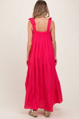 woman wearing a hot pink tiered maxi maternity dress with bow straps, showing a relaxed fit and flowy silhouette