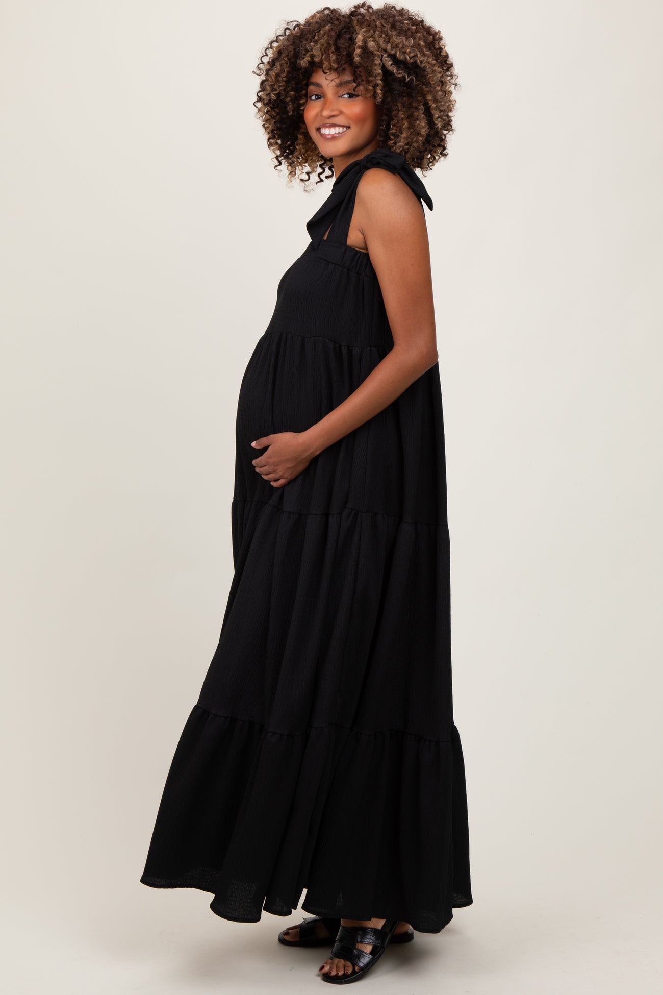 woman wearing a black tiered maxi dress with tie straps, showing off her baby bump