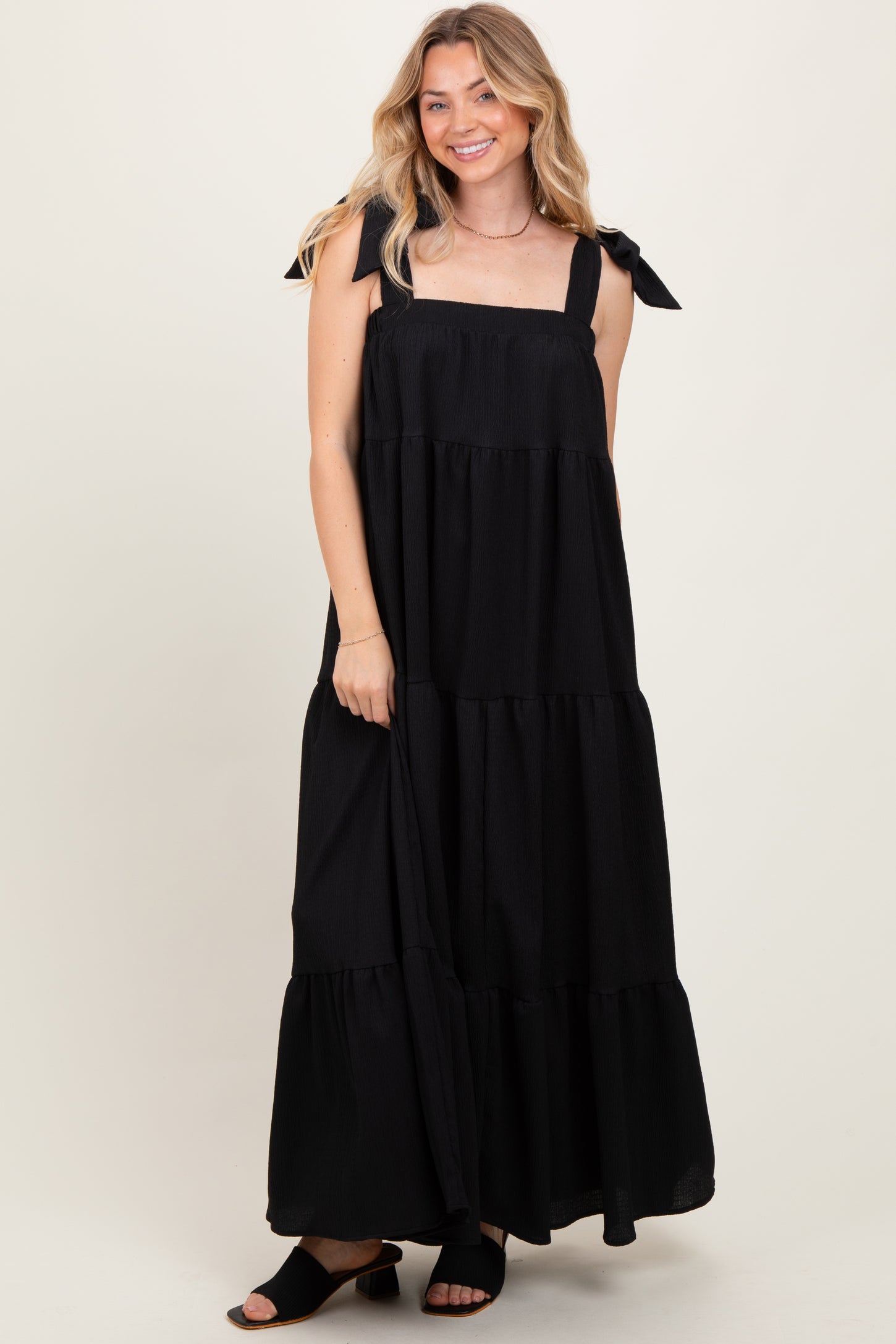 woman wearing a black tiered maxi dress with bow tie straps and a relaxed fit