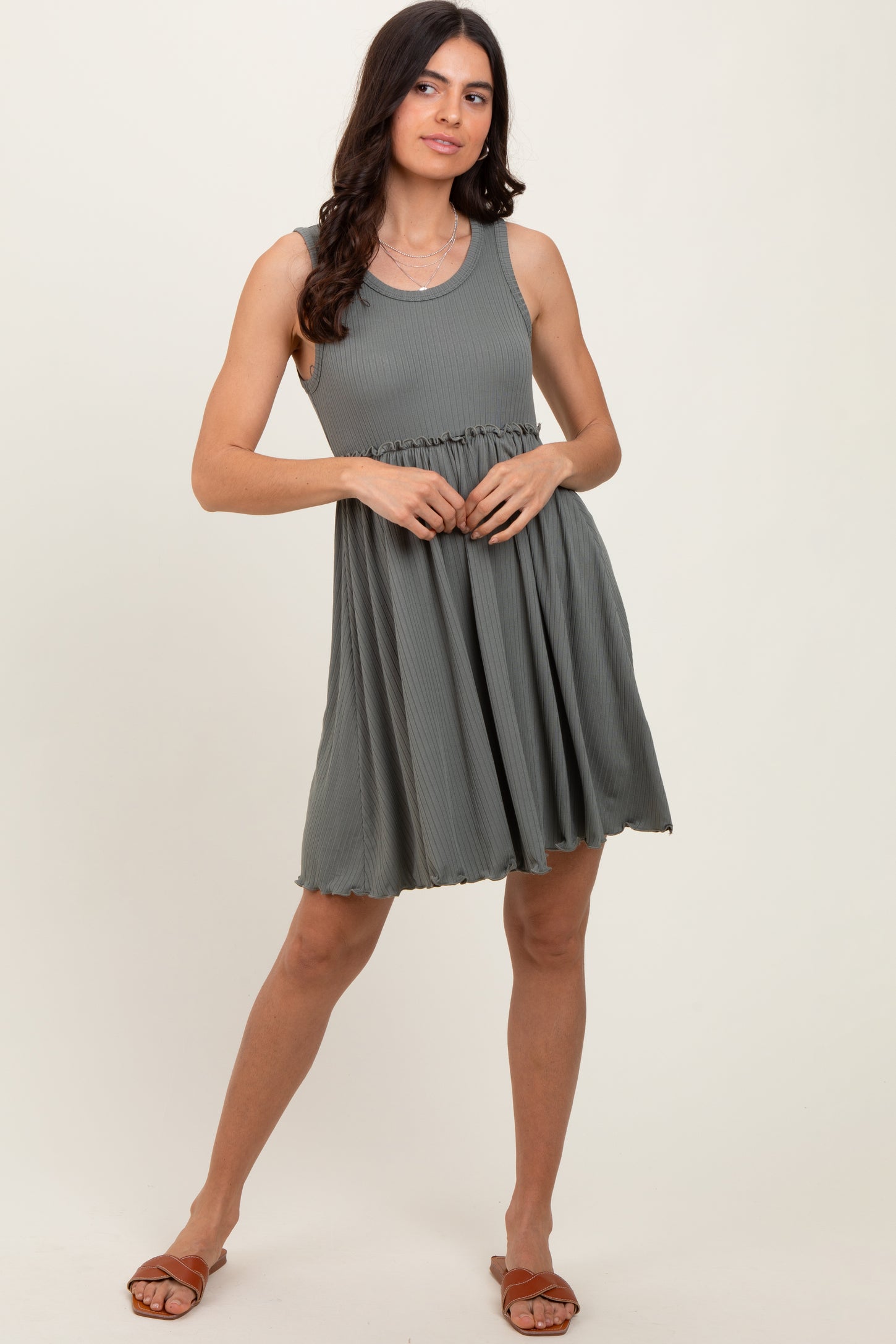 woman wearing a dark green sleeveless casual dress with a flared skirt and a fitted bodice