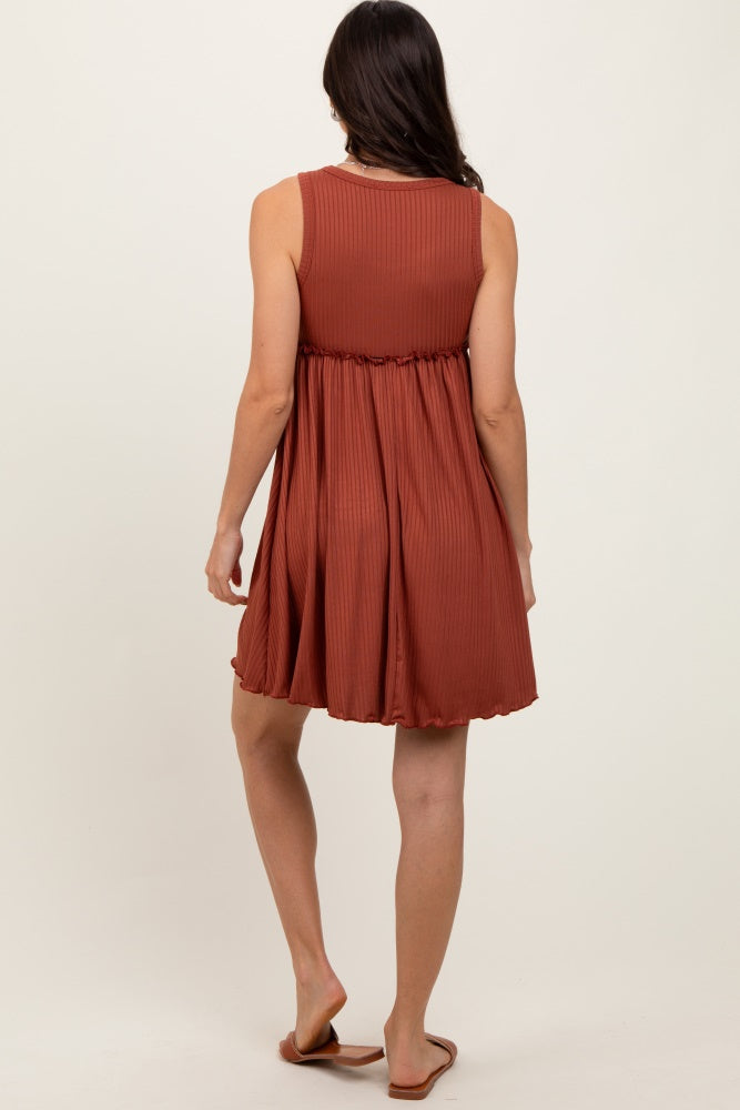 woman wearing a rust-colored sleeveless pleated dress with a flared skirt and a round neckline