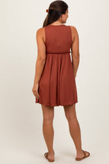woman wearing a rust-colored maternity dress with ribbed texture and elastic waist, showing a baby bump from the back