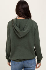 woman wearing a green ribbed hooded sweatshirt, facing away, paired with blue jeans