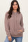 woman wearing a taupe ribbed hooded sweatshirt with a front pocket and drawstring details