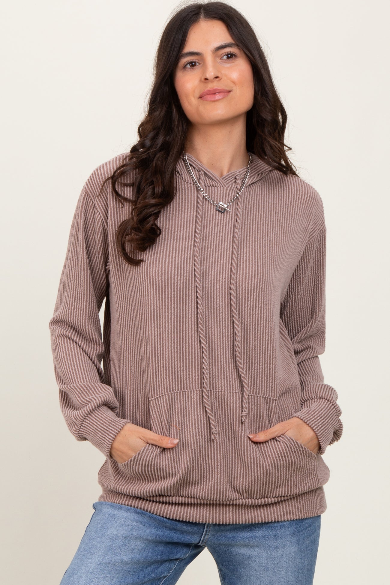 woman wearing a mauve ribbed hoodie with a drawstring and front pockets, styled with blue jeans