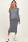 woman wearing a ribbed gray long sleeve maternity dress with a collar and button detail, showing her baby bump