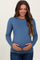 woman wearing a blue long sleeve maternity top and gently holding her baby bump