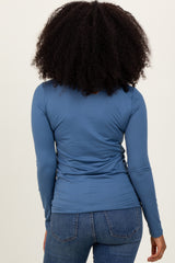 woman wearing a fitted long sleeve blue top, viewed from the back, paired with blue jeans