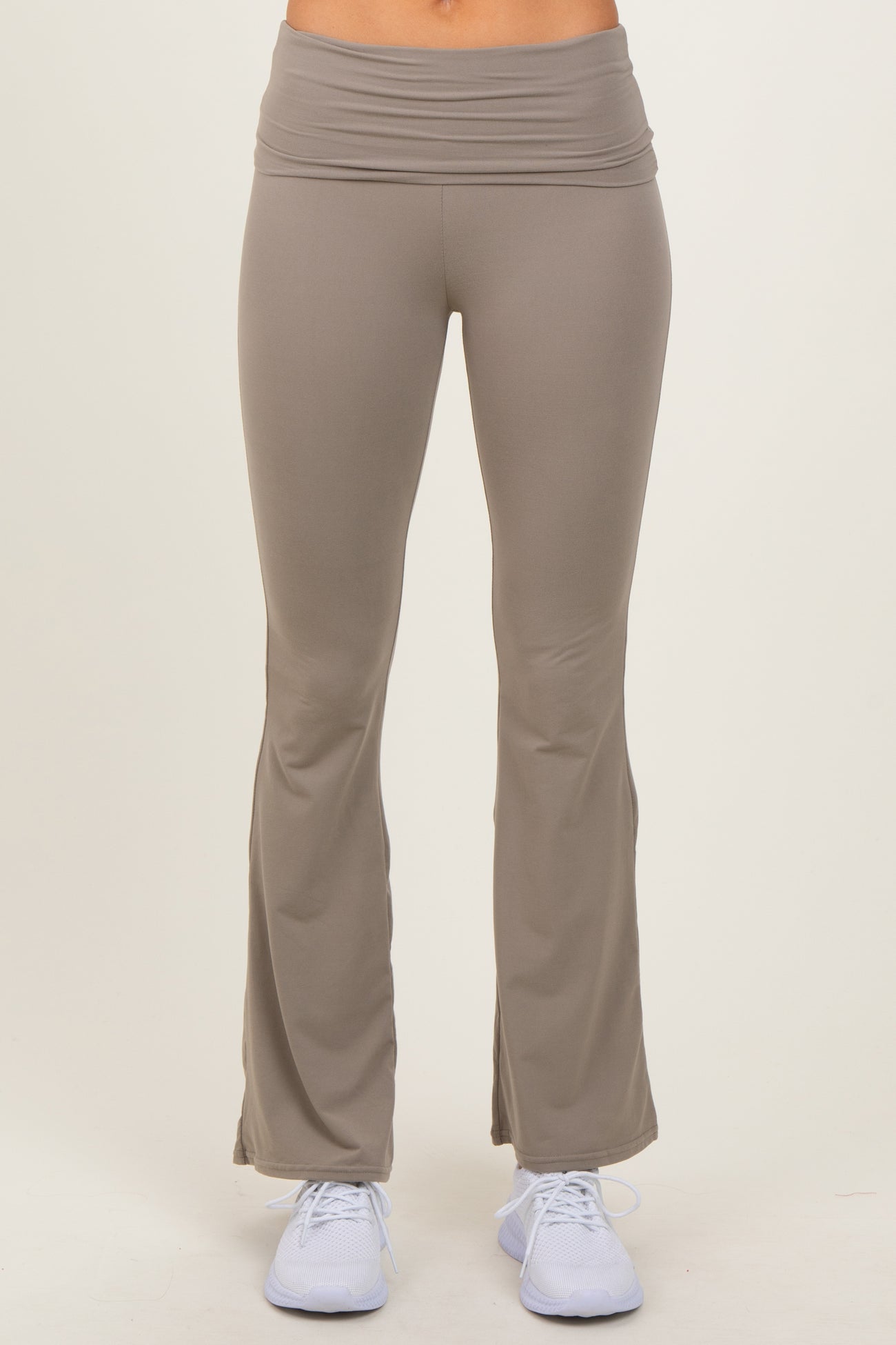 woman wearing light brown flared yoga pants with a wide waistband and white athletic shoes