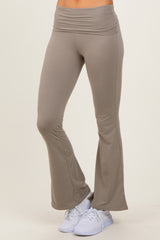 woman wearing light brown flared yoga pants paired with white athletic shoes on a beige background
