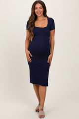 woman wearing a navy blue short sleeve maternity dress that highlights her baby bump