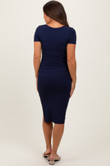 woman wearing a navy blue short sleeve maternity dress with a fitted silhouette and knee-length hem