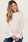 woman wearing a cream striped maternity sweater with a relaxed fit and balloon sleeves, smiling at the camera