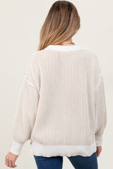 woman wearing a cream and beige striped maternity sweater with a relaxed fit and balloon sleeves