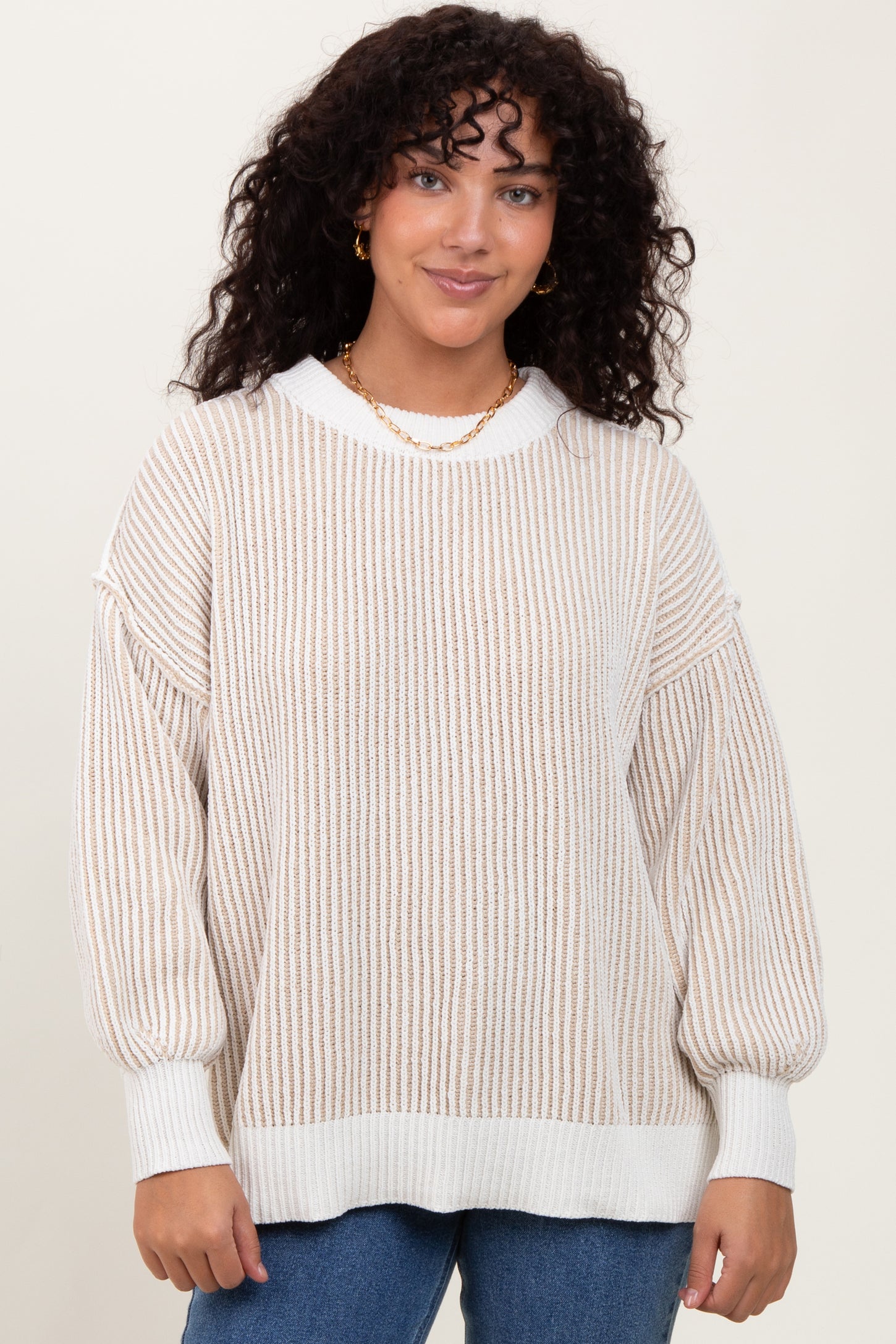 woman wearing a cream and beige striped oversized sweater with balloon sleeves and a ribbed hem