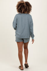 woman wearing a blue checkered maternity loungewear set with long sleeves and shorts, showing her back