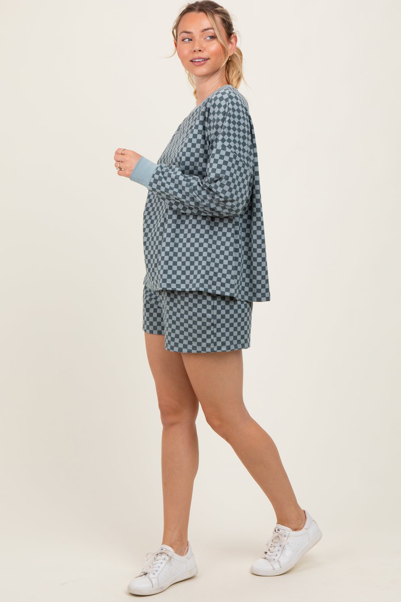 woman wearing a blue checkered loungewear set with long sleeve top and shorts, styled with white sneakers