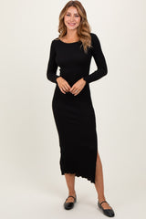 woman wearing a black ribbed long sleeve midi dress with a side slit and scalloped hem