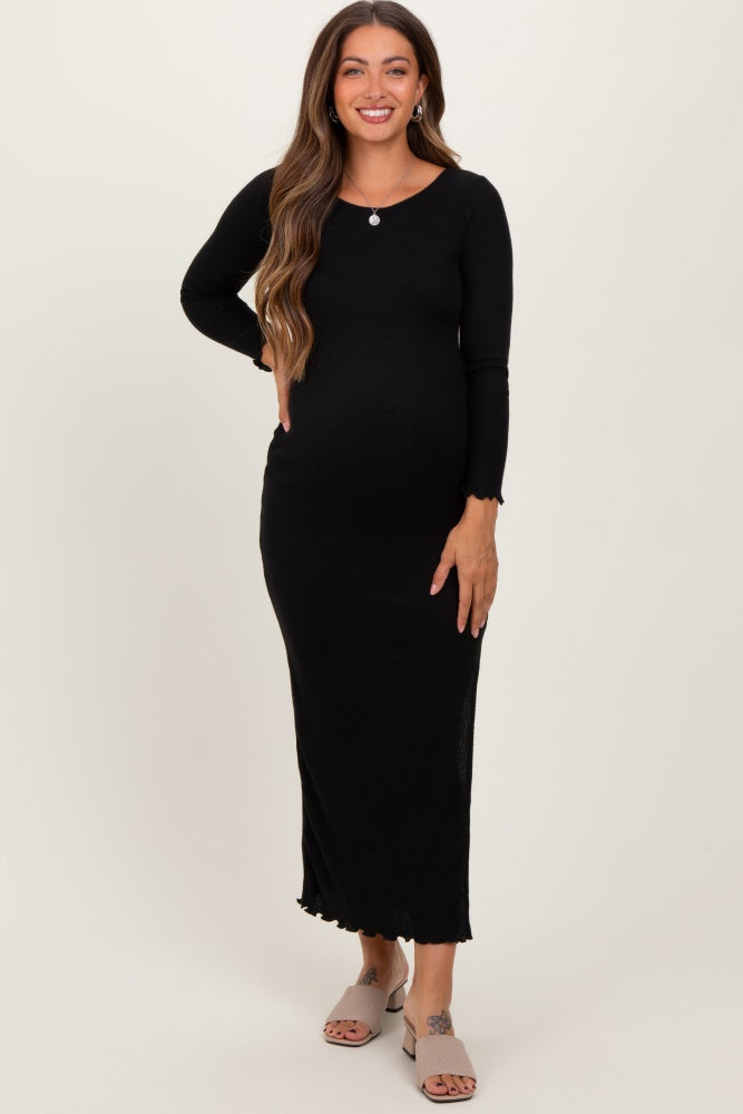 woman wearing a black long sleeve maternity dress with a fitted silhouette and scalloped hem, showcasing her baby bump