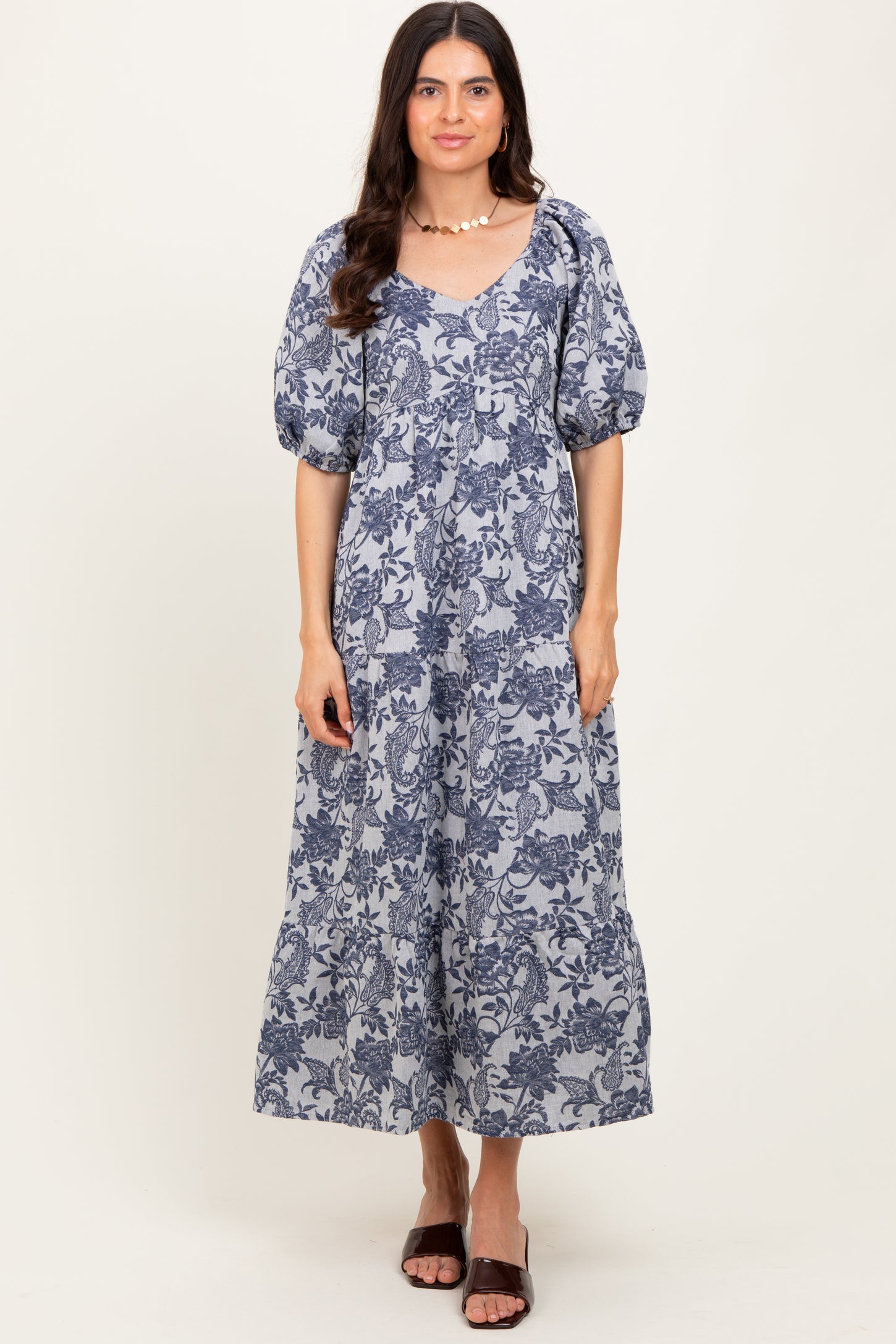 woman wearing a navy blue floral maxi dress with puff sleeves and a v-neckline, standing and smiling