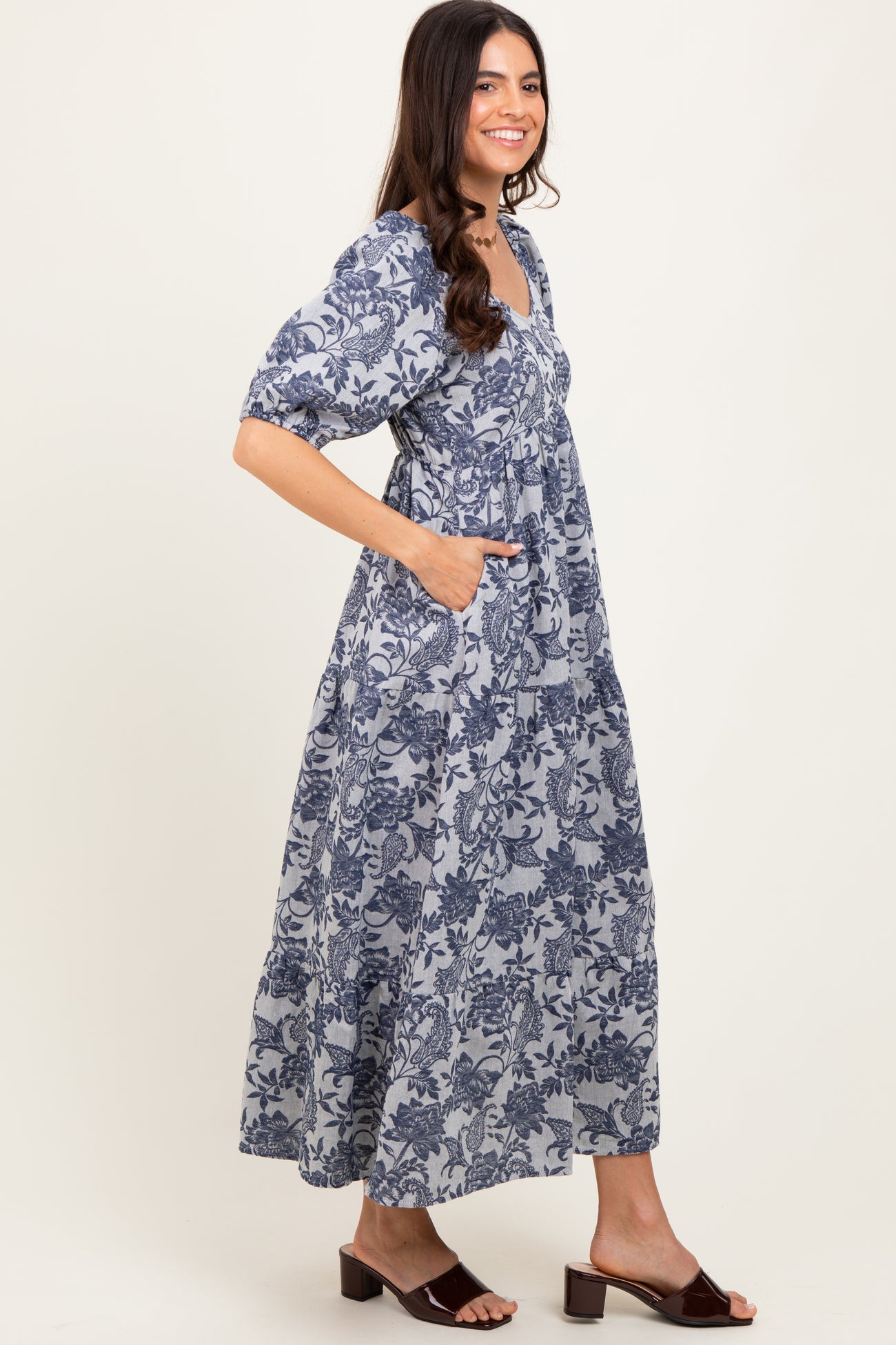 woman wearing a navy blue floral print maxi dress with short puff sleeves and side pockets