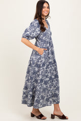 woman wearing a navy blue floral print maxi dress with short puff sleeves and side pockets