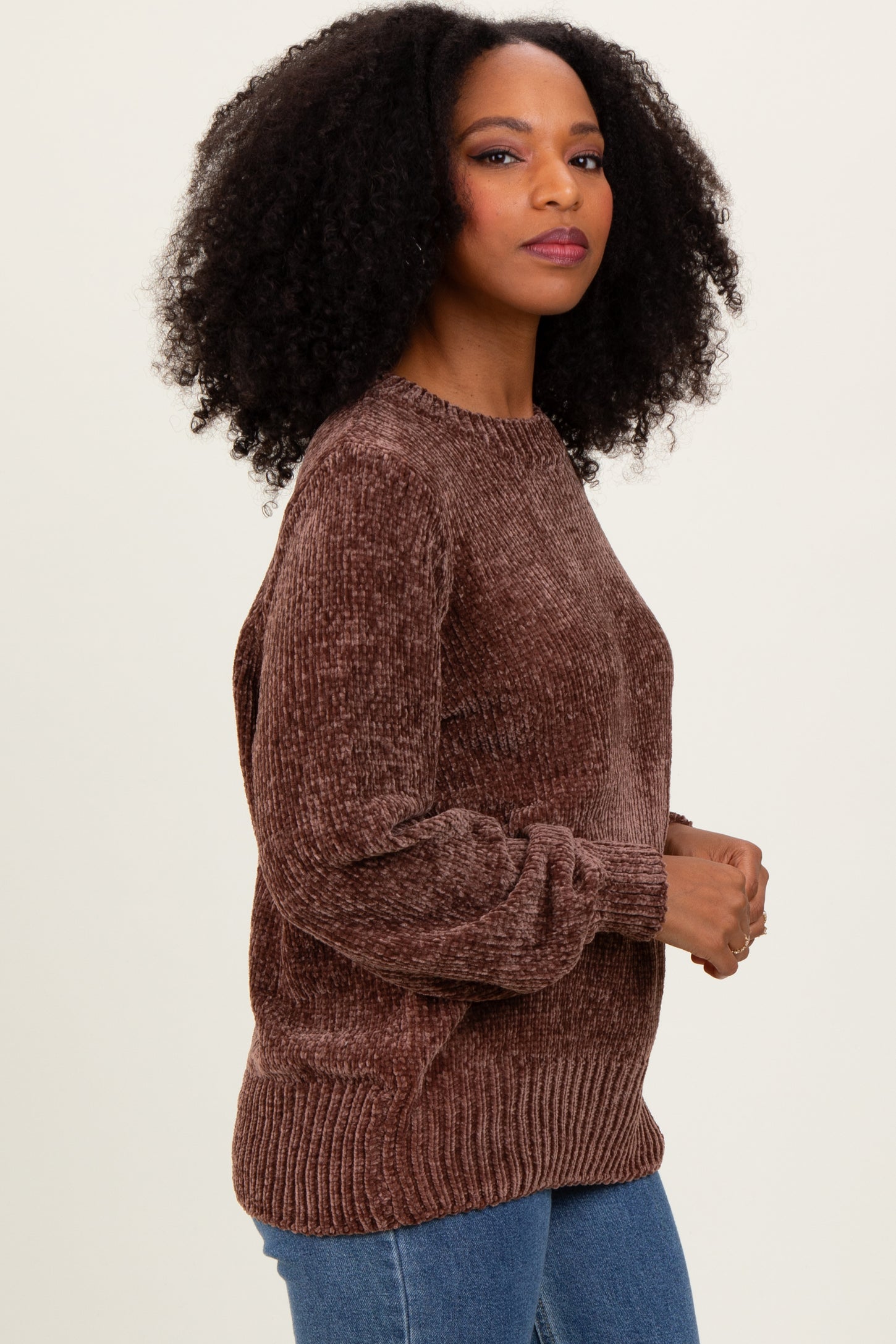 woman wearing a brown textured sweater with long sleeves and a relaxed fit, paired with blue jeans