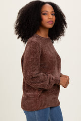 woman wearing a brown textured sweater with long sleeves and a relaxed fit, paired with blue jeans