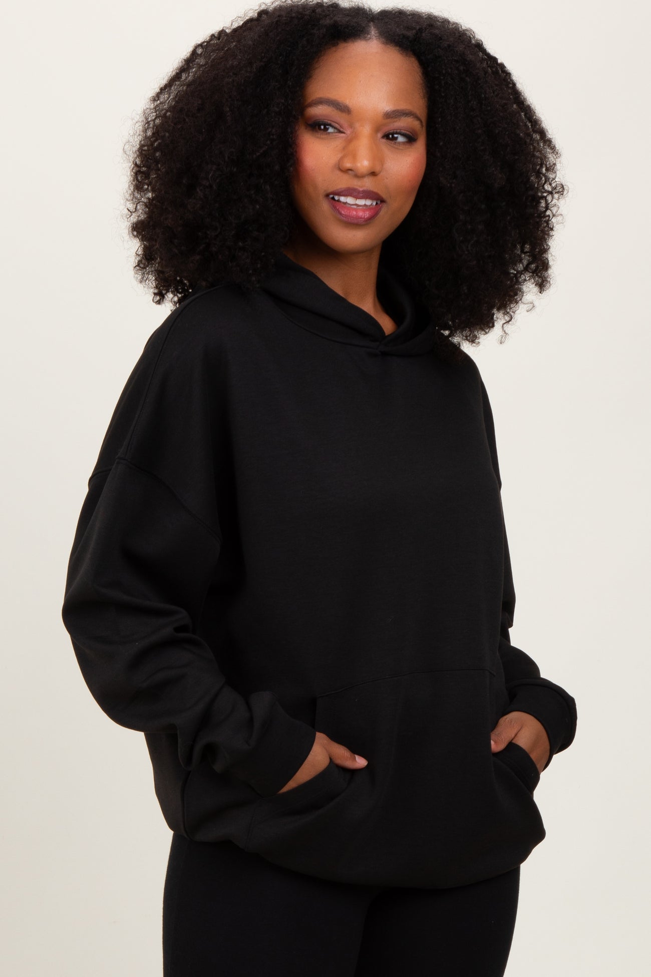 woman wearing a black oversized hoodie with a front pocket and a hood