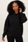 woman wearing a black oversized hoodie with a front pocket and a hood, styled with black leggings