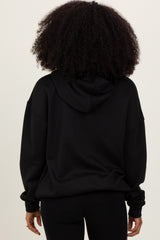 woman wearing a black oversized hoodie, viewed from the back with a relaxed fit and a hood