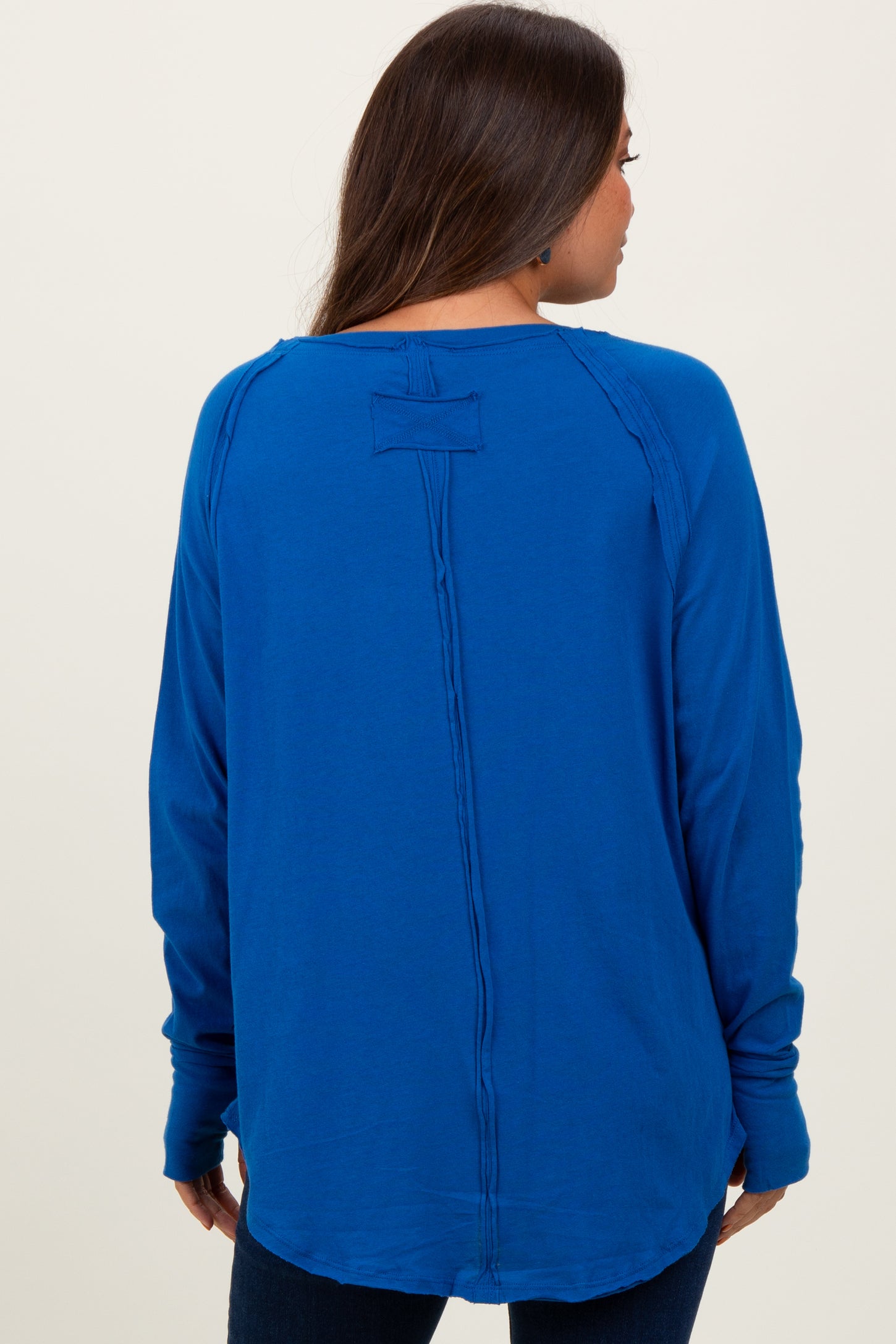 woman wearing a bright blue long sleeve maternity top, showing the back view and relaxed fit