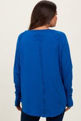 woman wearing a bright blue long sleeve maternity top, showing the back view and relaxed fit