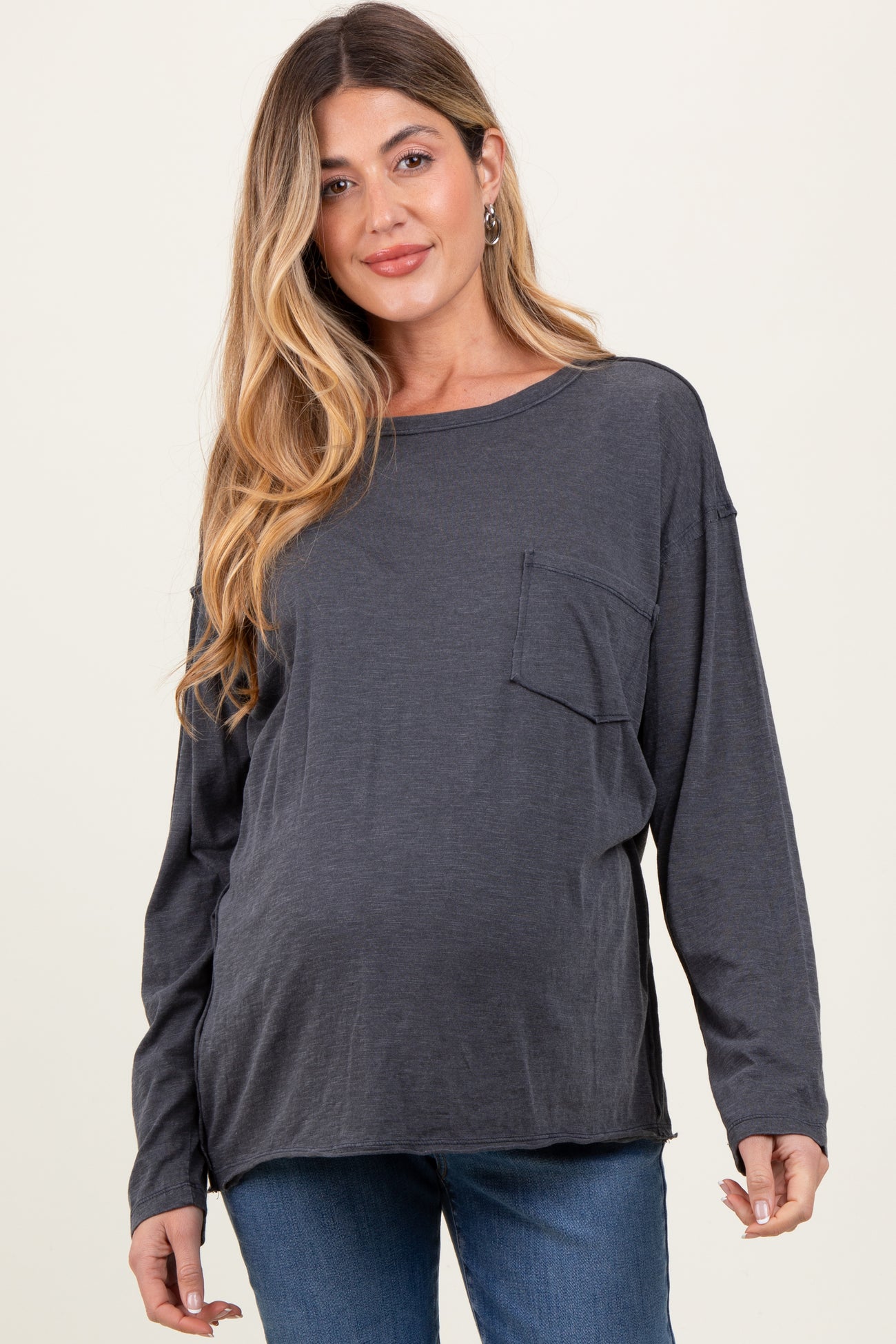 woman wearing a dark gray long sleeve maternity top with a front pocket and showing her baby bump